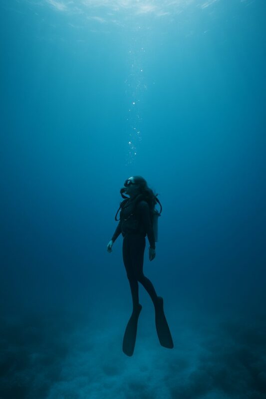 Taucherin schwebt im blauen Wasser.