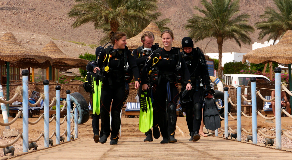 Taucher vor dem Tauchgang am Hausriff Dahab, Lagona Divers Team mit Ausrüstung und Flossen auf dem Steg im Roten Meer