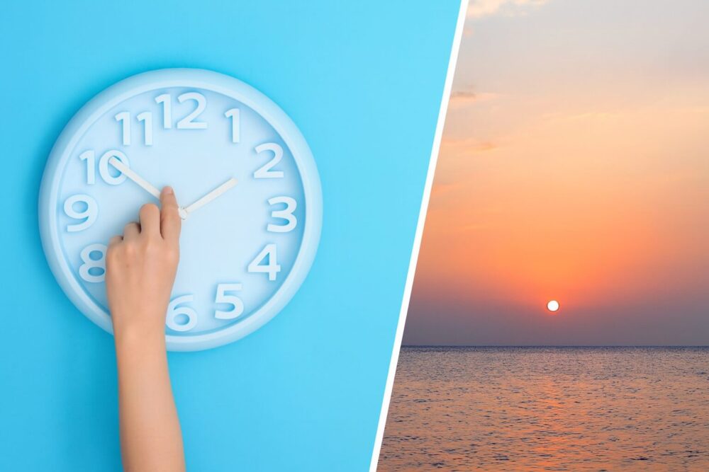 Eine Hand stellt die Uhr auf Winterzeit, im Hintergrund sieht man einen Sonnenuntergang am Meer.